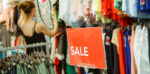A woman browsing through a clothes rail looking at sale items