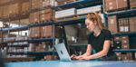 Woman in a warehouse working on a laptop