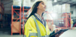 A supply chain manager holding a tablet device wearing a hi vis jacket in a warehouse