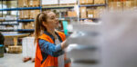 A woman wearing a high vis jacket working in a warehouse